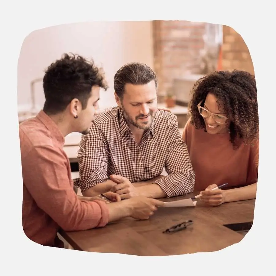 Three colleagues discussing documents at a round table, collaborating on a financial plan.