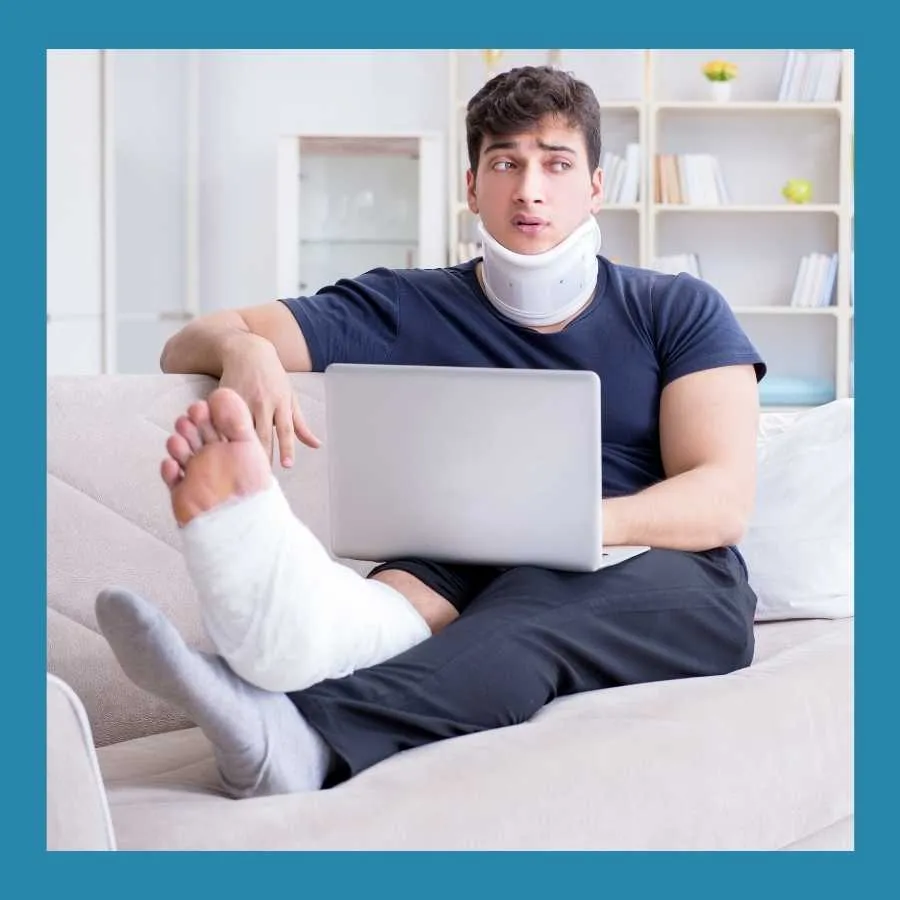 Man with a neck brace and leg cast working on a laptop while seated on a couch.