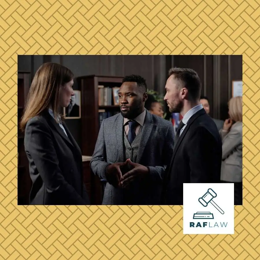 Three attorneys engaged in a serious discussion in a law office, with the RAF LAW logo in the corner.