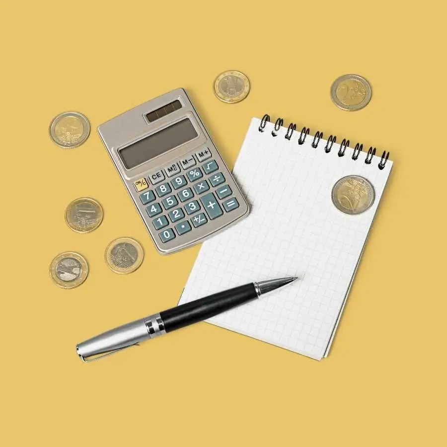 Calculator, notepad, and pen with coins on yellow background for financial planning