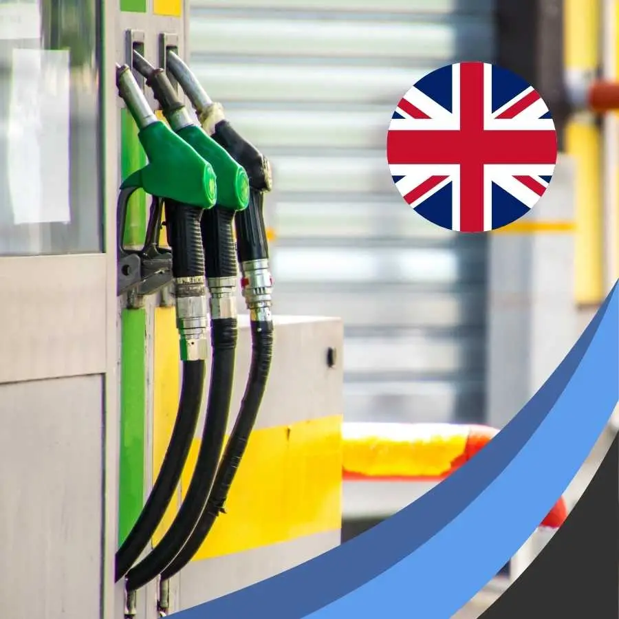 Fuel pump nozzles at a station with the UK flag emblem indicating a comparison of fuel policies.