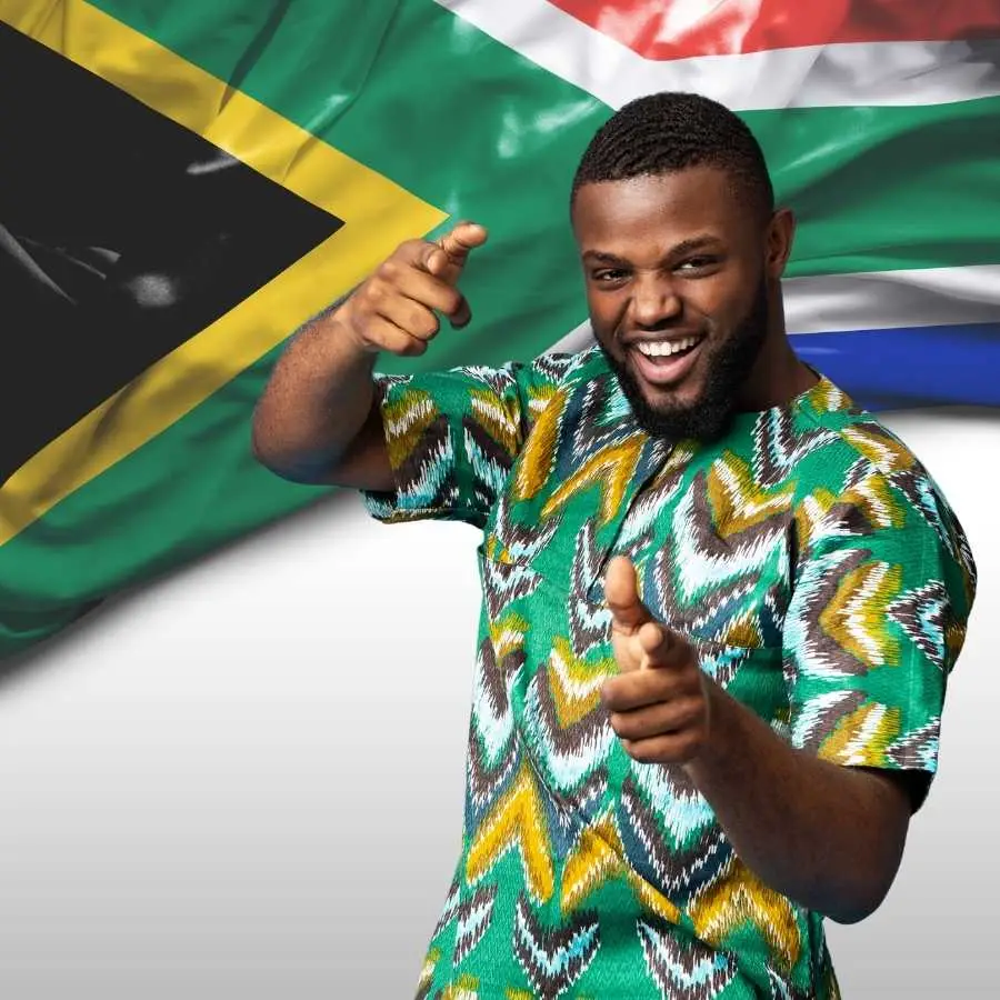 Joyful South African taxi driver with thumbs up in front of the national flag.
