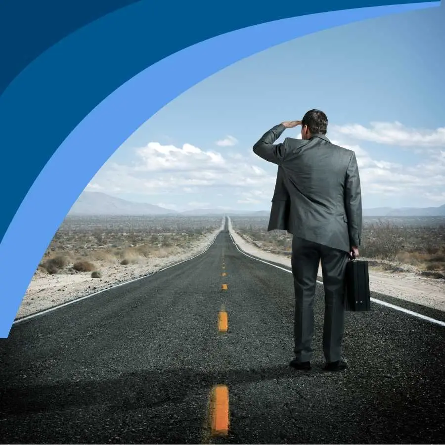 Businessman standing on an open road, looking towards the horizon, symbolizing strategic foresight.