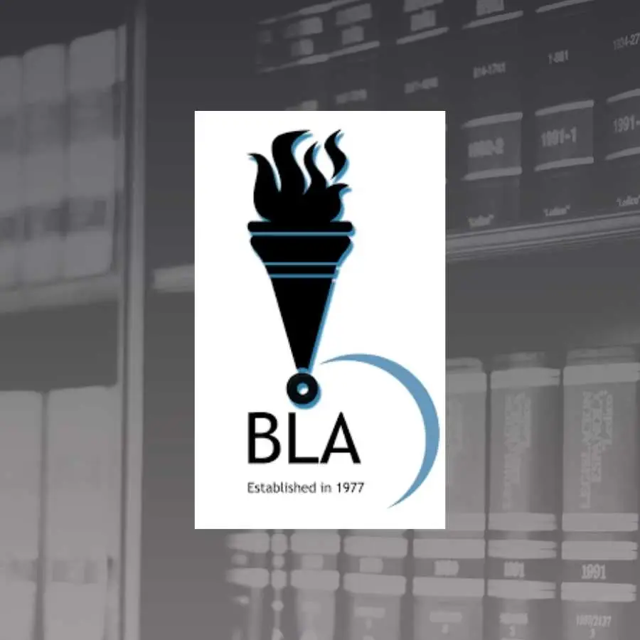 Logo of the Black Lawyers Association established in 1977 in front of a law library, symbolizing the representation and support for black legal professionals in South Africa.