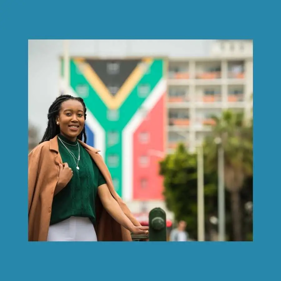 Young woman in front of a colorful building with South African flag