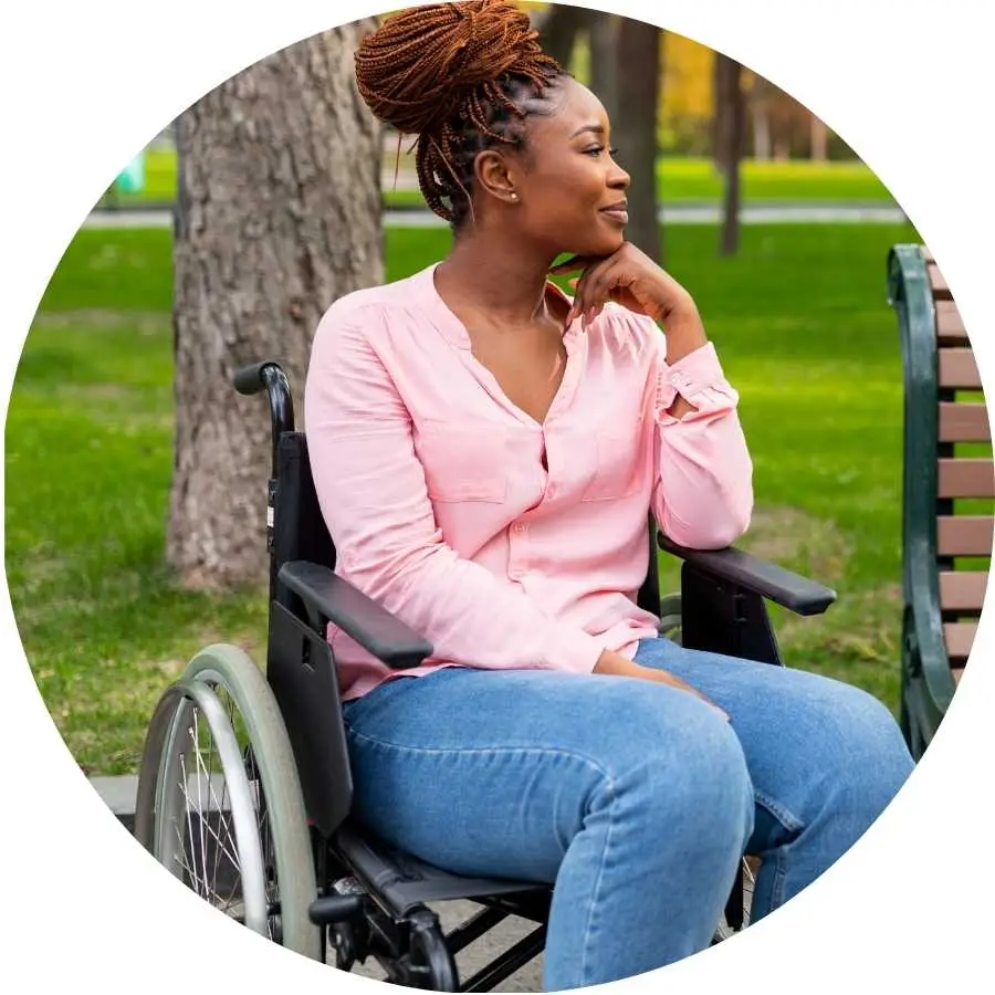 Woman in a wheelchair looking thoughtful in a park