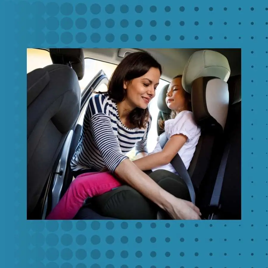 Mother fastening seat belt for her daughter in the car