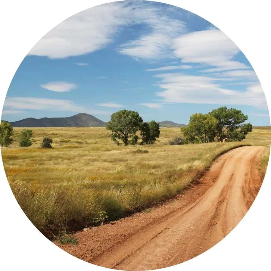 Rural road winding through a scenic landscape with mountains in the background