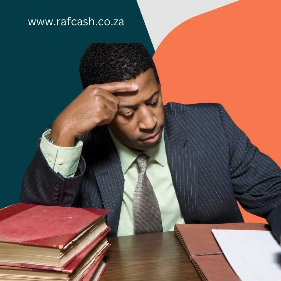 Frustrated businessman with a headache sitting at a desk with stacks of legal documents