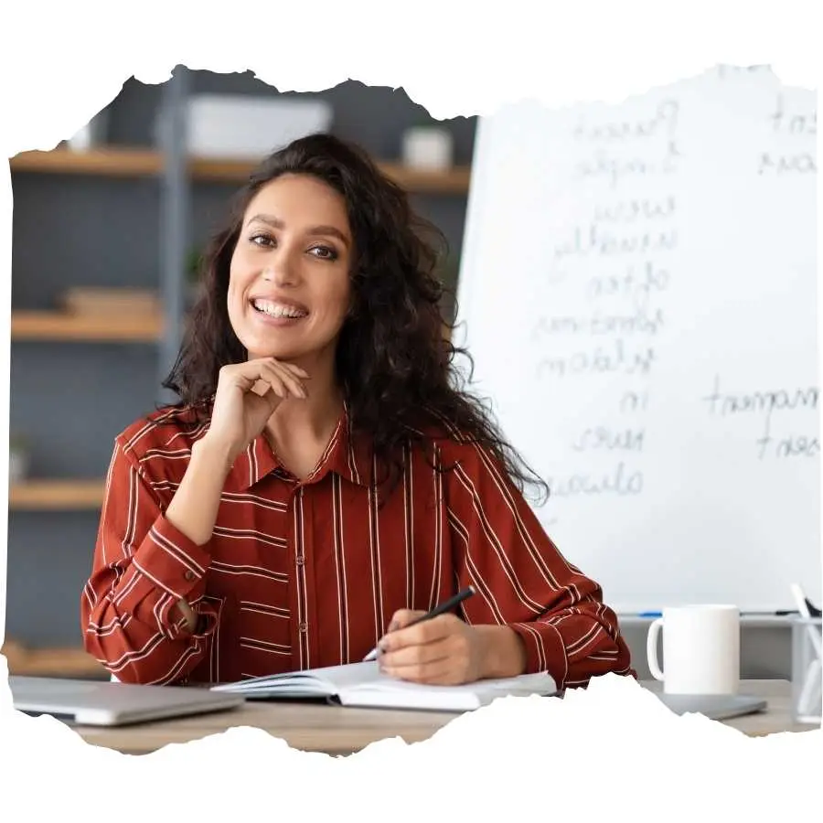 Confident teacher smiling at her desk in a modern classroom