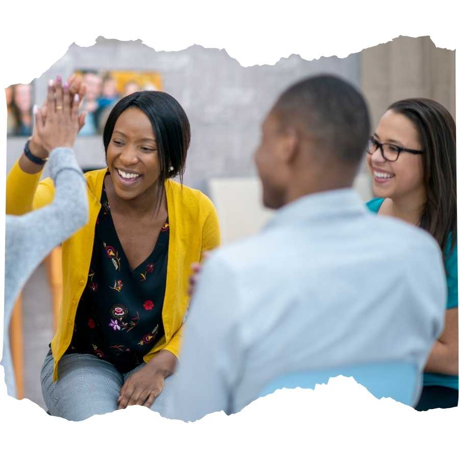 Group therapy session with a joyful high-five between participants