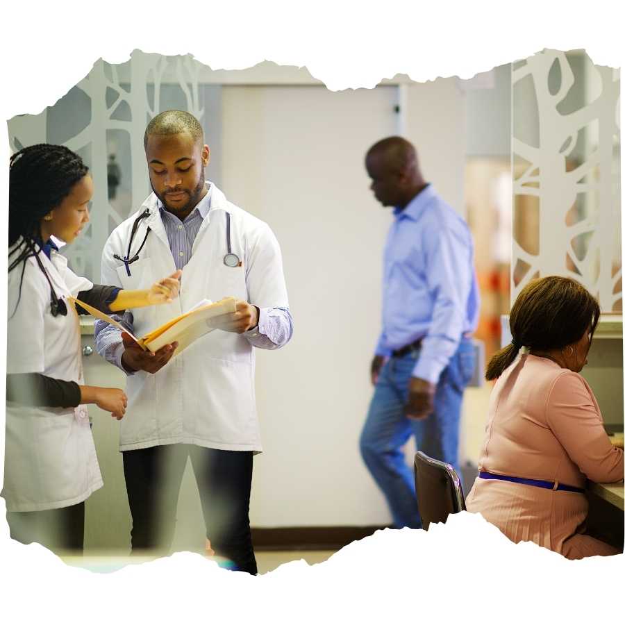 Healthcare professionals discussing patient documents in a busy hospital corridor