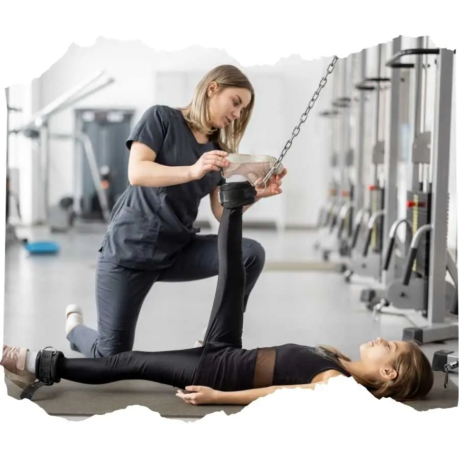 Physical therapist assisting a young woman with leg exercises in a gym