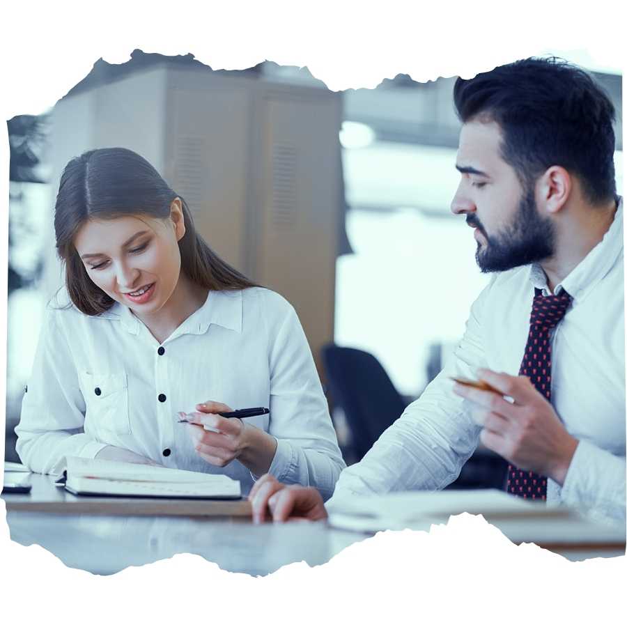 Two professionals discussing documents at a desk in an office setting