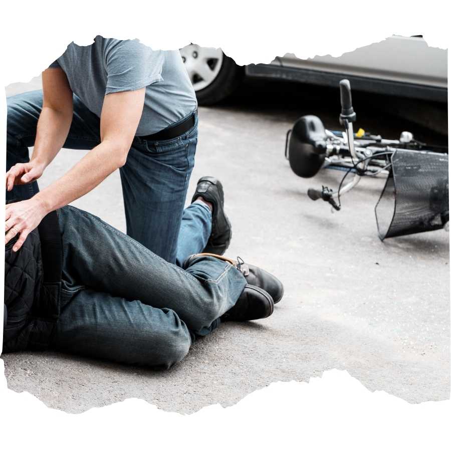 A man injured in a road accident with a motorcycle wreckage in the background