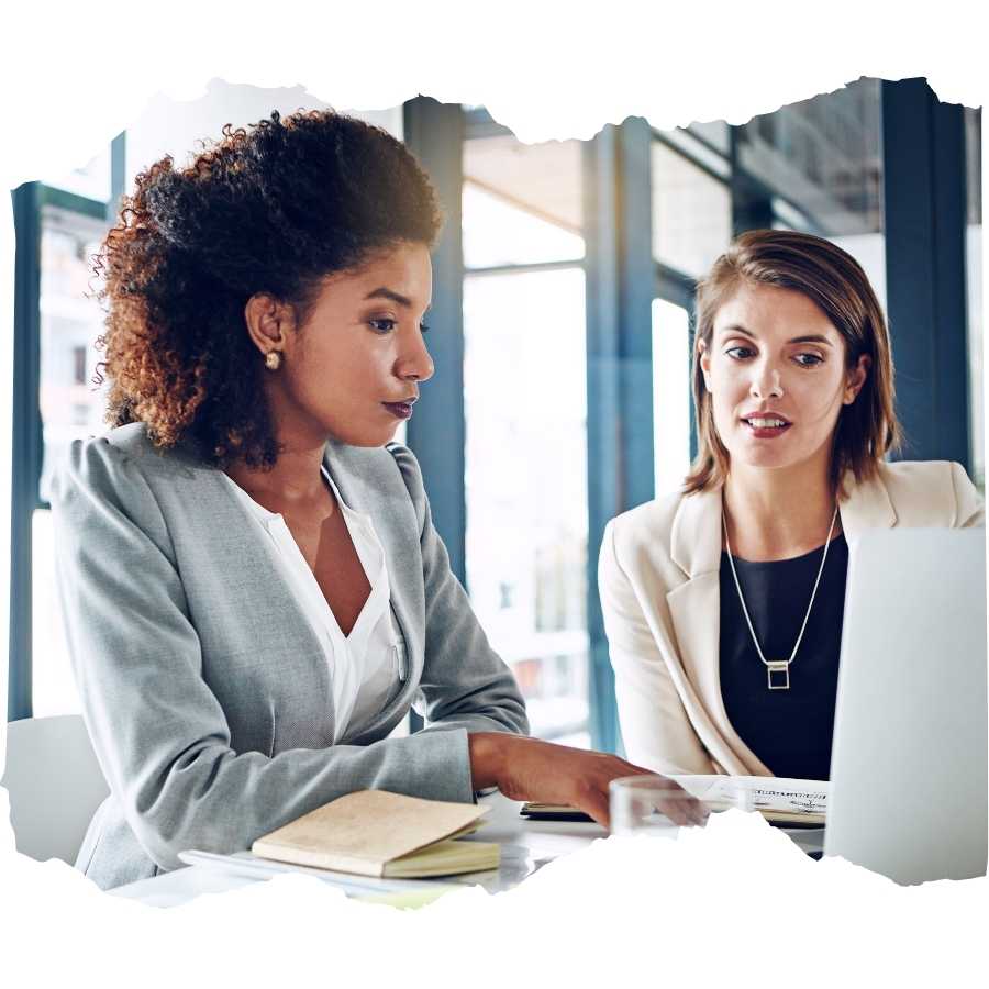 Two professional women discussing work on a laptop in an office