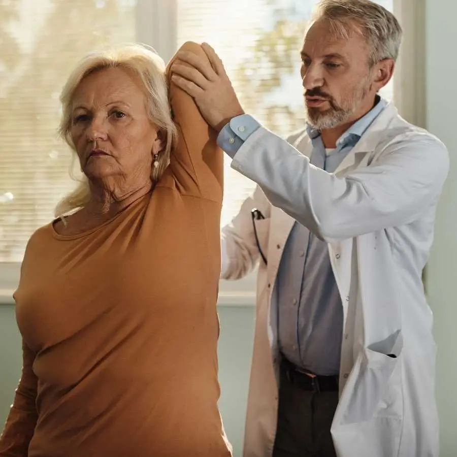 Doctor assisting an injured woman with physical therapy for her shoulder