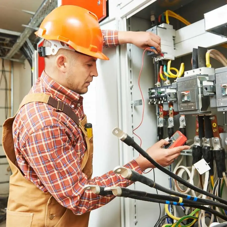 Electrician wearing a hard hat working on electrical panels