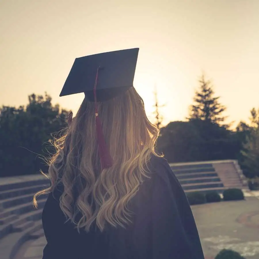 Graduate in cap and gown looking towards the sunset