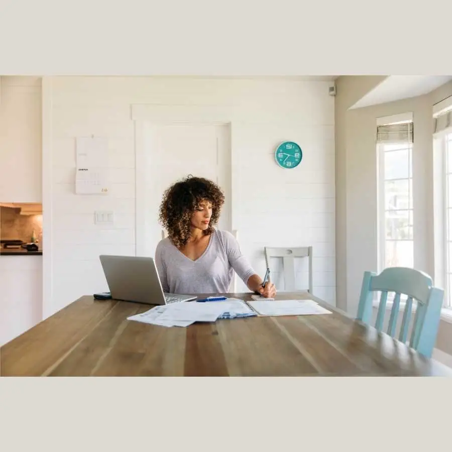 Woman working on financial documents at home with laptop